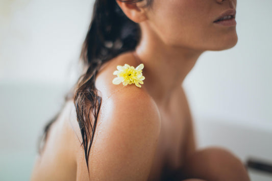 woman with a flower on her shoulder promoting skincare