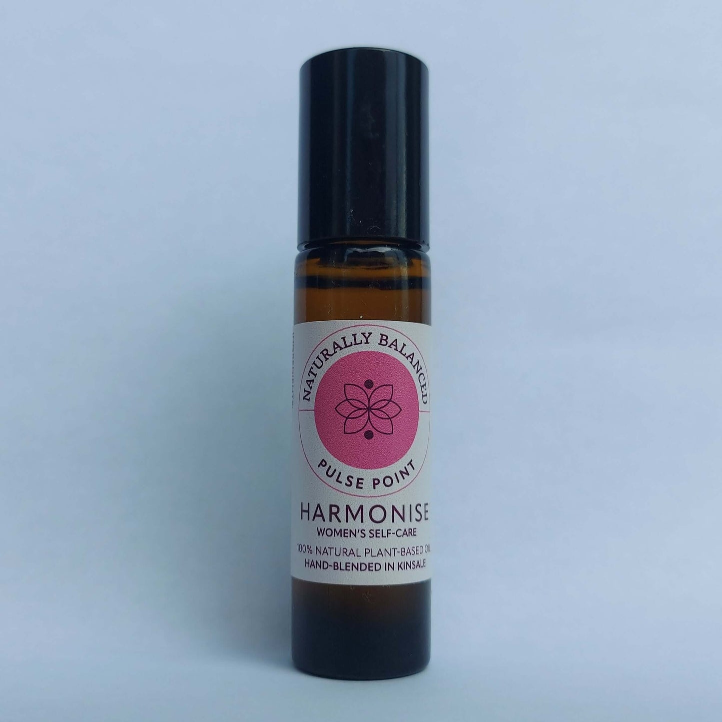 Small roller bottle with a pink label on a light gray background