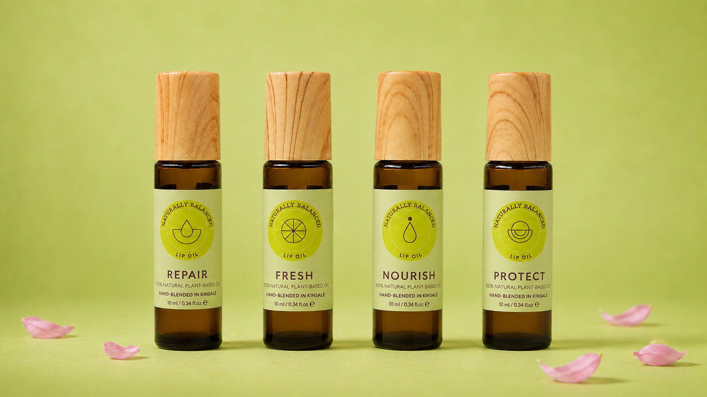 Four bottles of natural skincare products with wooden caps on a green background