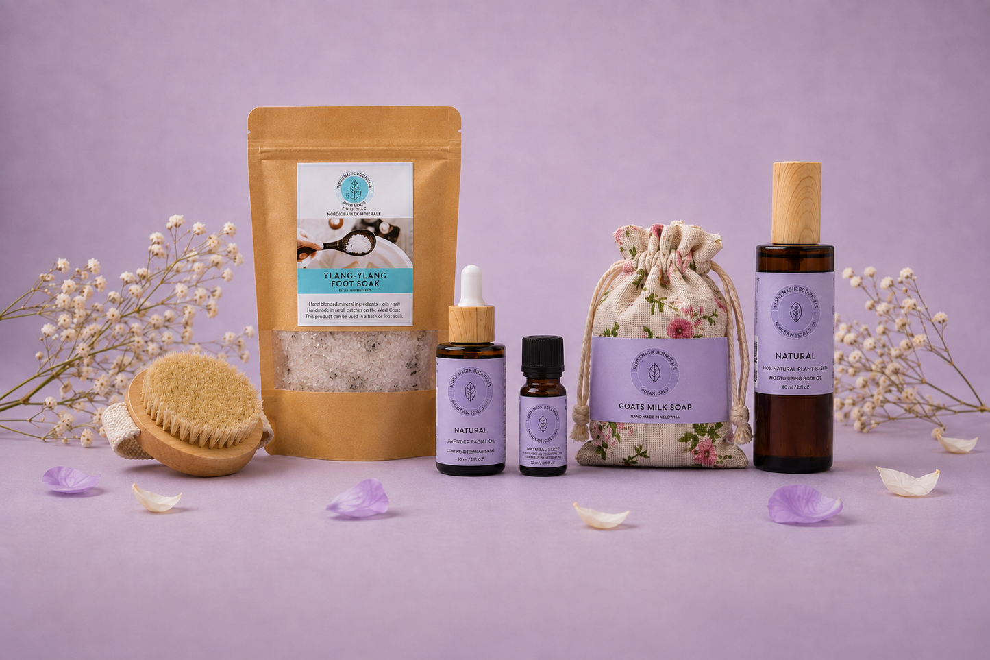 A spa gift set featuring a gold stand-up pouch, two amber dropper bottles, a floral drawstring bag, and an amber bottle with a wooden cap, arranged on a lavender surface with dried flowers and petals against a lavender background.