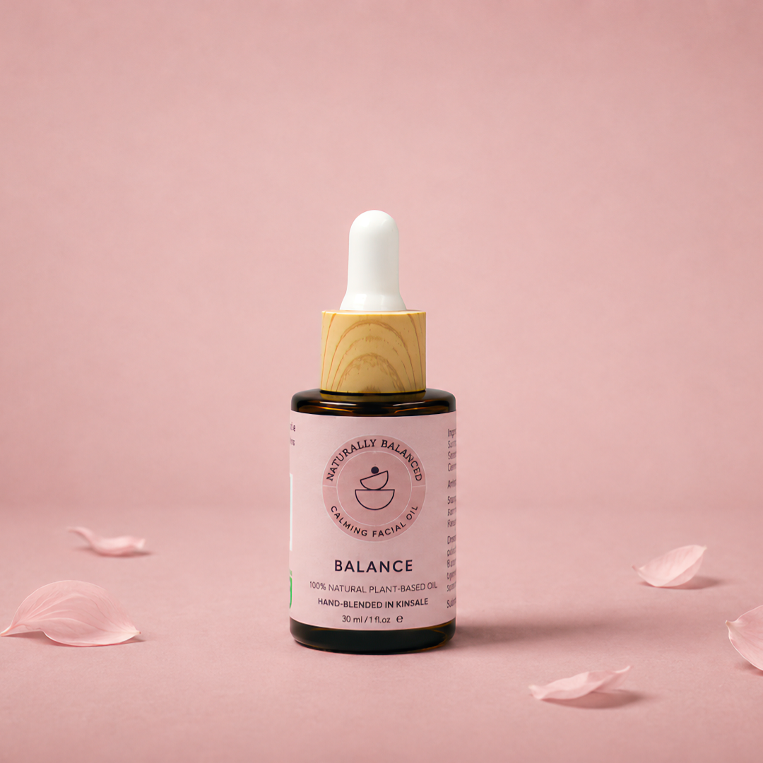 Bottle of 'Balance' serum with dropper on a pink background with scattered rose petals
