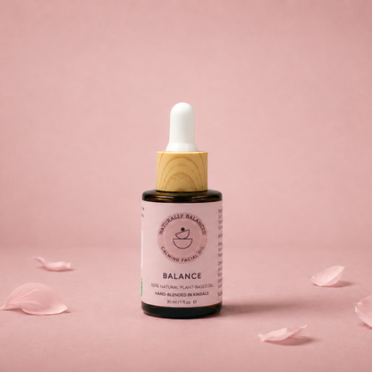 Bottle of 'Balance' serum with dropper on a pink background with scattered rose petals