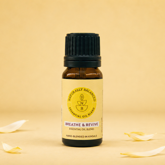 Small essential oil bottle labeled 'Breathe & Revive' on a beige background with scattered leaves.