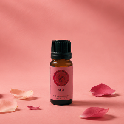 Small bottle of essential oil with pink flower petals on a pink background