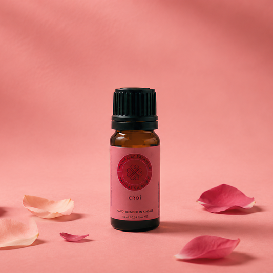 Small bottle of essential oil with pink flower petals on a pink background