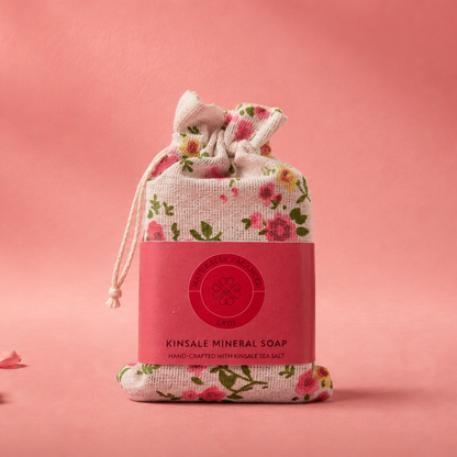 Pink soap bar in a floral drawstring bag on a pink background