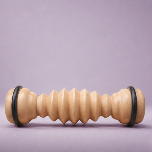 Wooden massage roller with black ends on a purple background