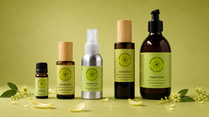 Collection of 'Maintain' skincare products on a green background with flowers.