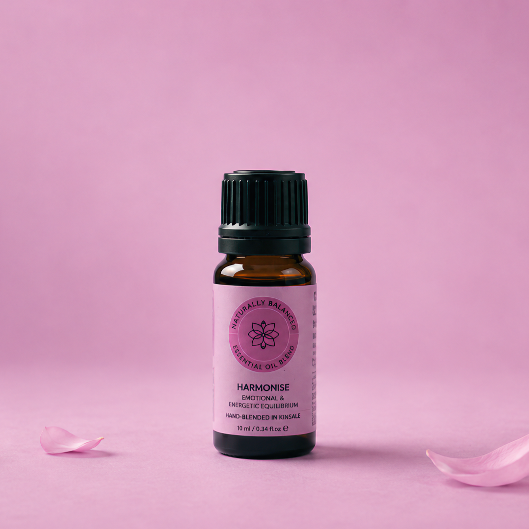 Essential oil bottle with pink label on a pink background with rose petals