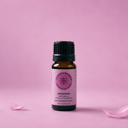 Essential oil bottle with pink label on a pink background with rose petals