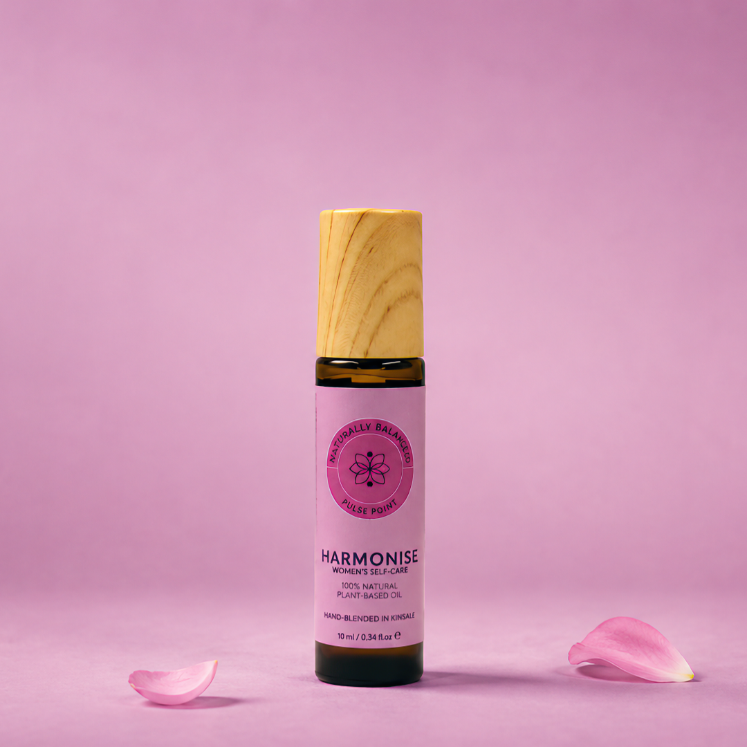 Bottle of Harmonie on a pink background with scattered rose petals