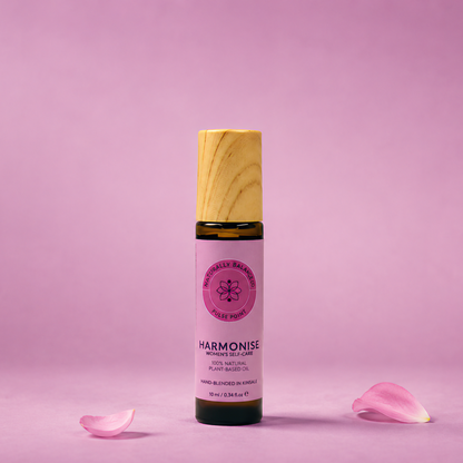 Bottle of Harmonie on a pink background with scattered rose petals