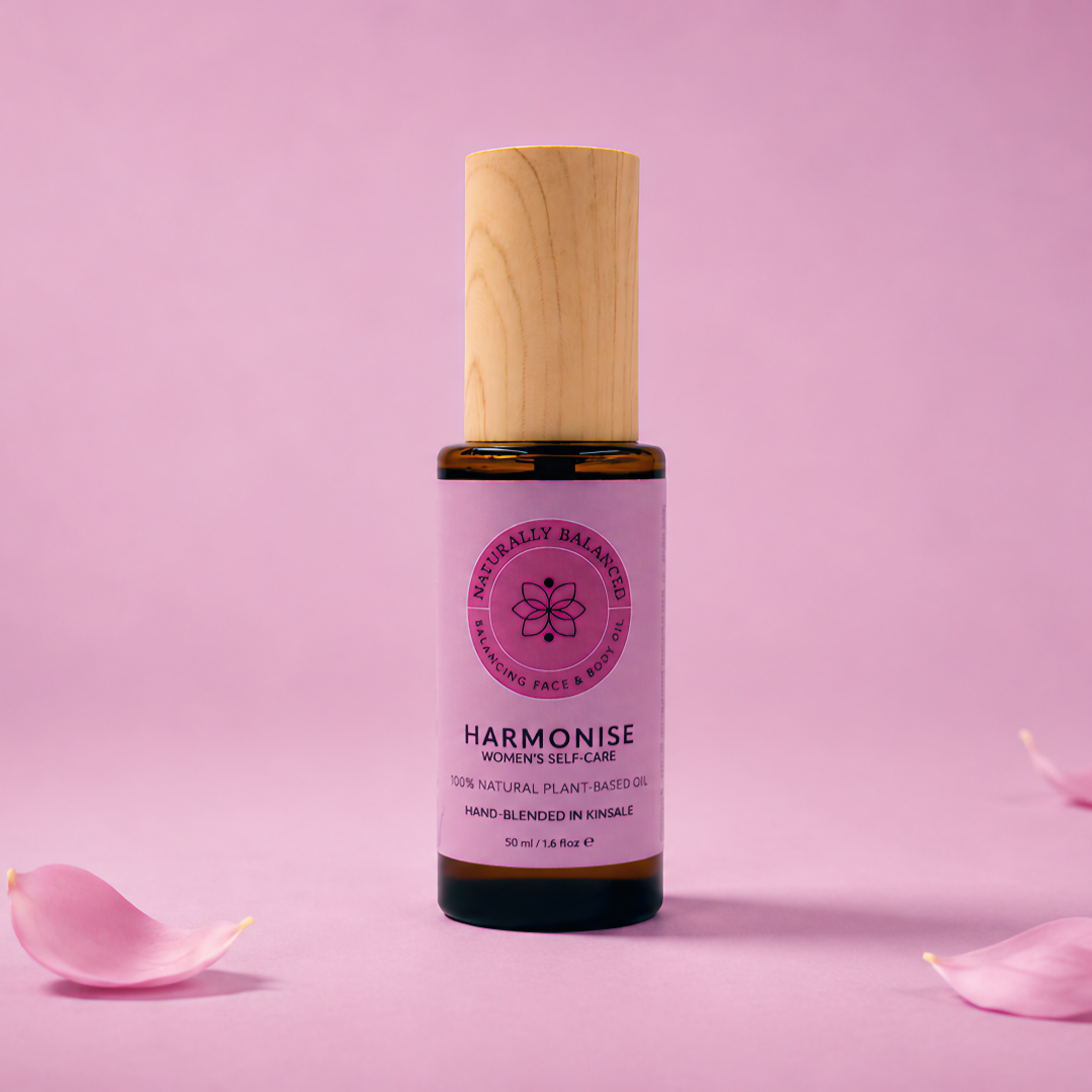 Bottle of 'Harmonise' product with wooden cap on a pink background with scattered petals
