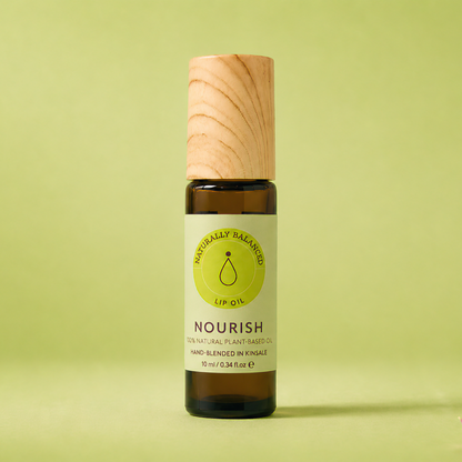 Bottle of Nourish essential oil on a light green background with pink petals.