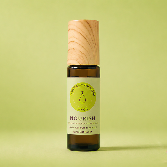 Bottle of Nourish essential oil on a light green background with pink petals.
