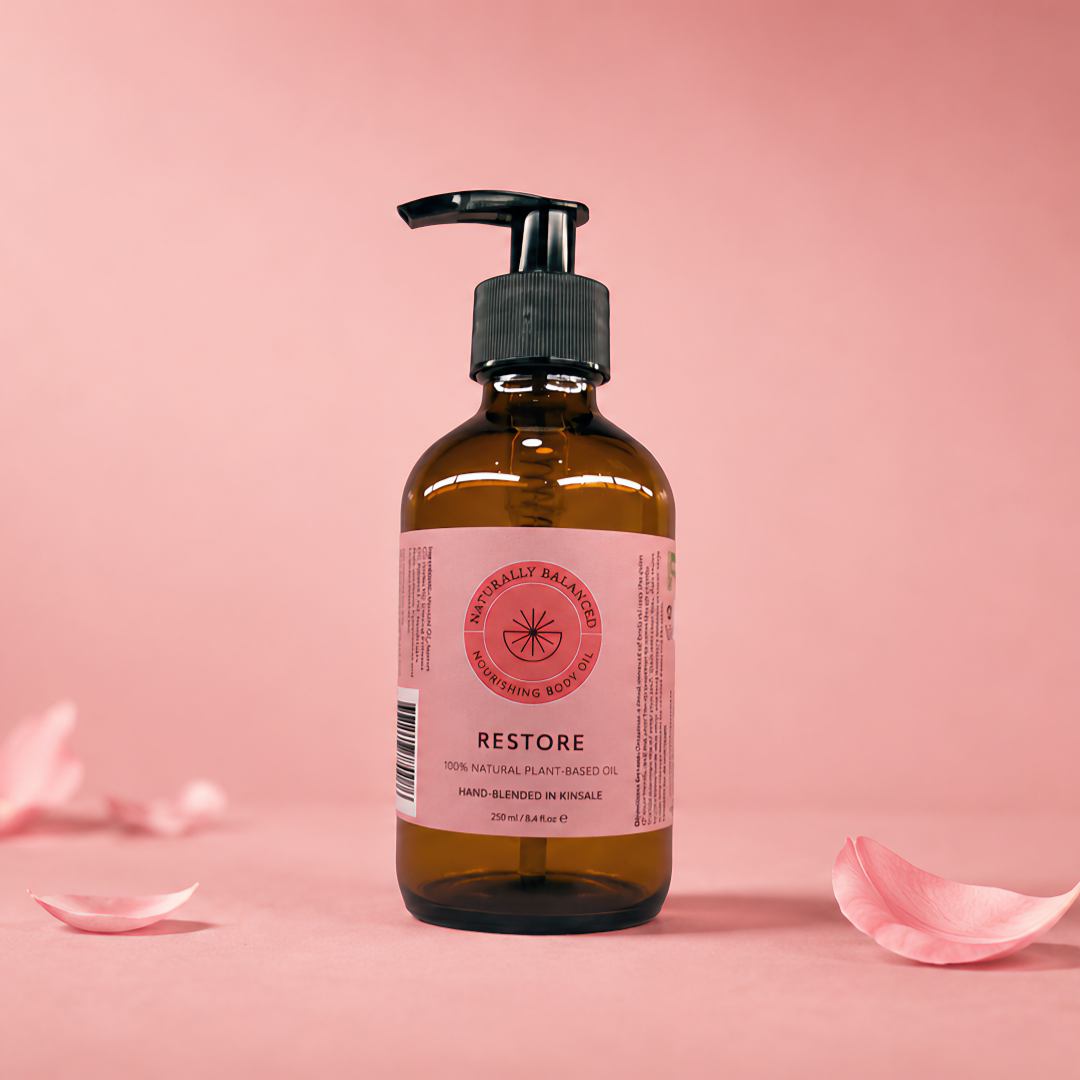 Bottle of 'Restore' with pink label on a pink background with scattered rose petals