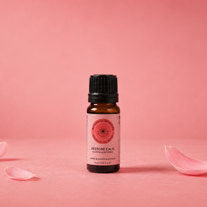 Small bottle of Restore Calm essential oil with pink petals on a pink background
