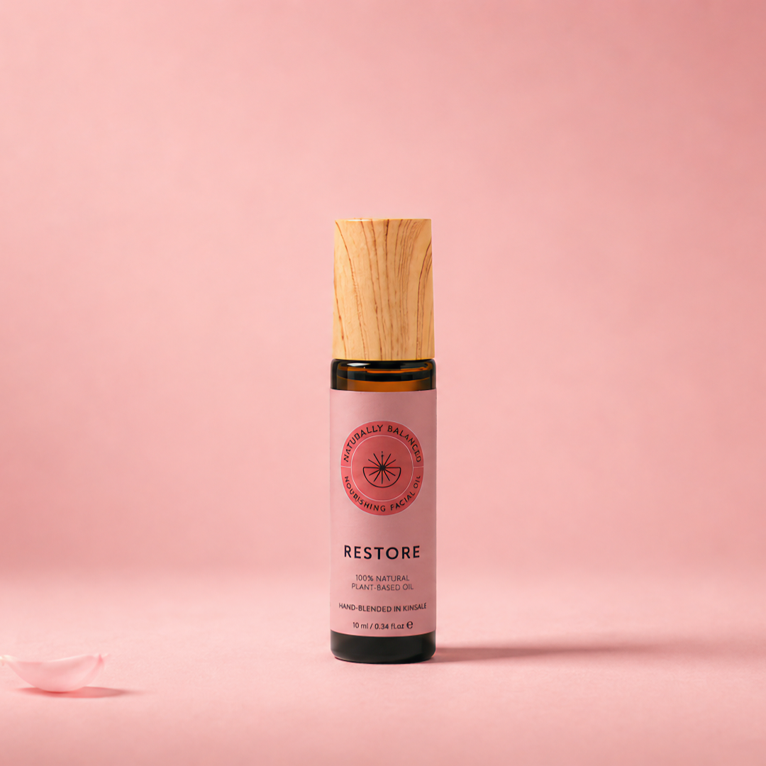 Roll-on bottle labeled 'Restore' on a pink background with rose petals.