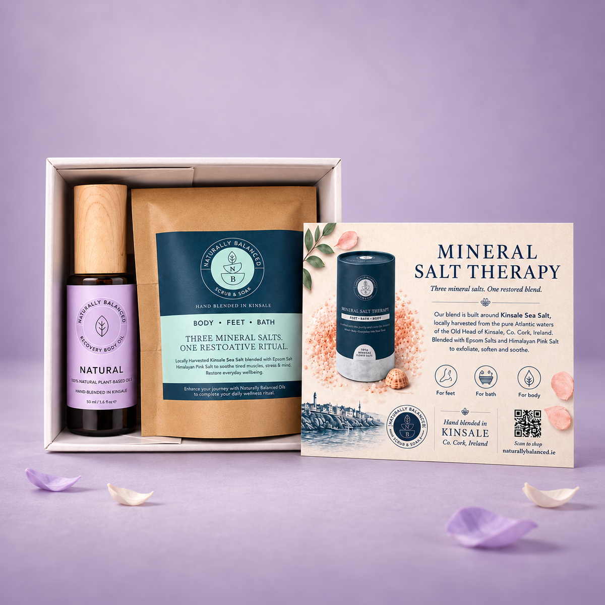 A mineral salt therapy gift set displayed in a white box on a lavender background. The set includes a small bottle of natural sea salt, a brown paper bag of three mineral salts, a blue tin of body and feet bath salts, and an informational card.